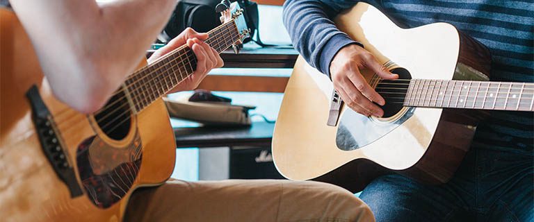 Guitars two people testing out guitars