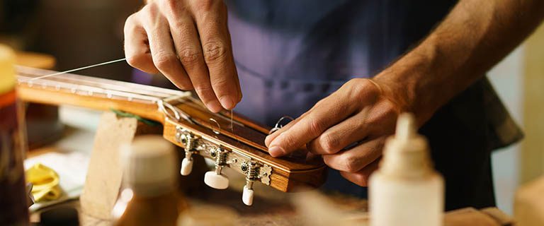 Guy restringing a guitar